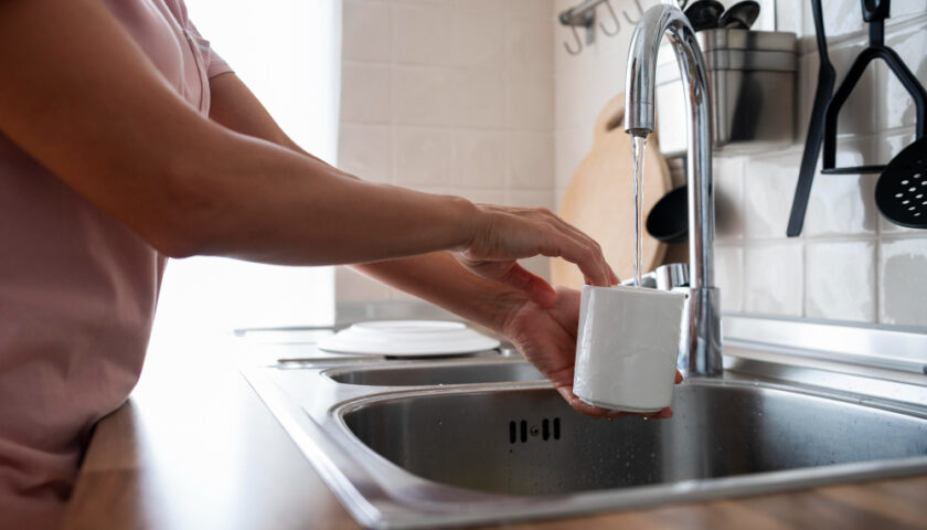 une femme remplit une tasse avec de l'eau du rbinet